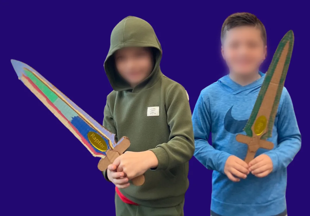 Two young makers holding decorated cardboard swords they built, faces blurred
